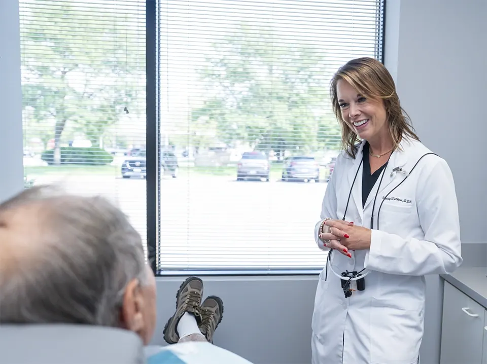 Dr. Stacey Wolken talking with a patient in a treatment room.